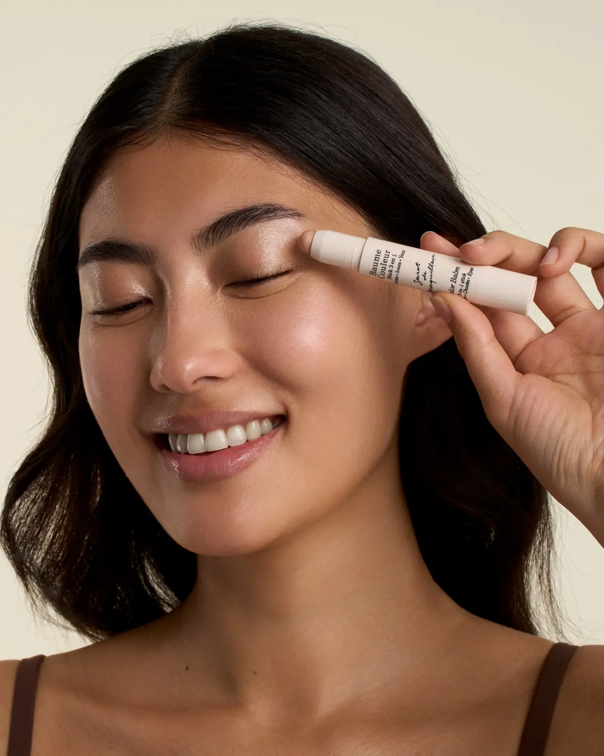 Modelo aplicando el bálsamo iluminador Baume Couleur Stick 3 en 1 Beige nacarado de Embryolisse