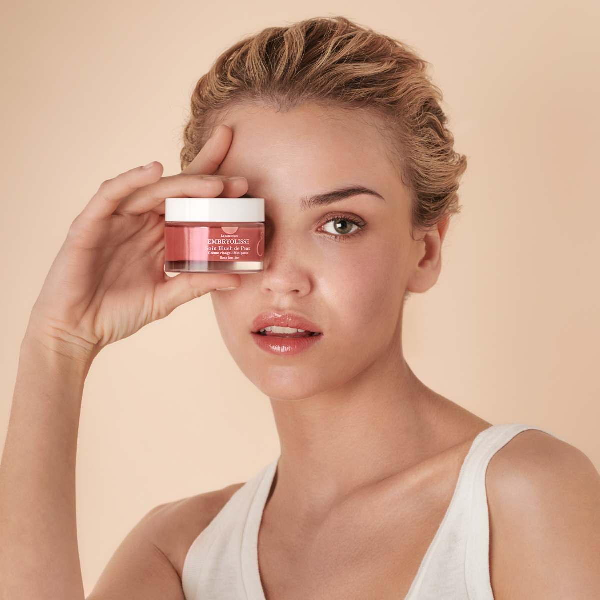 Modelo con piel luminosa sosteniendo Soin Blush de Peau Rose de EMBRYOLISSE